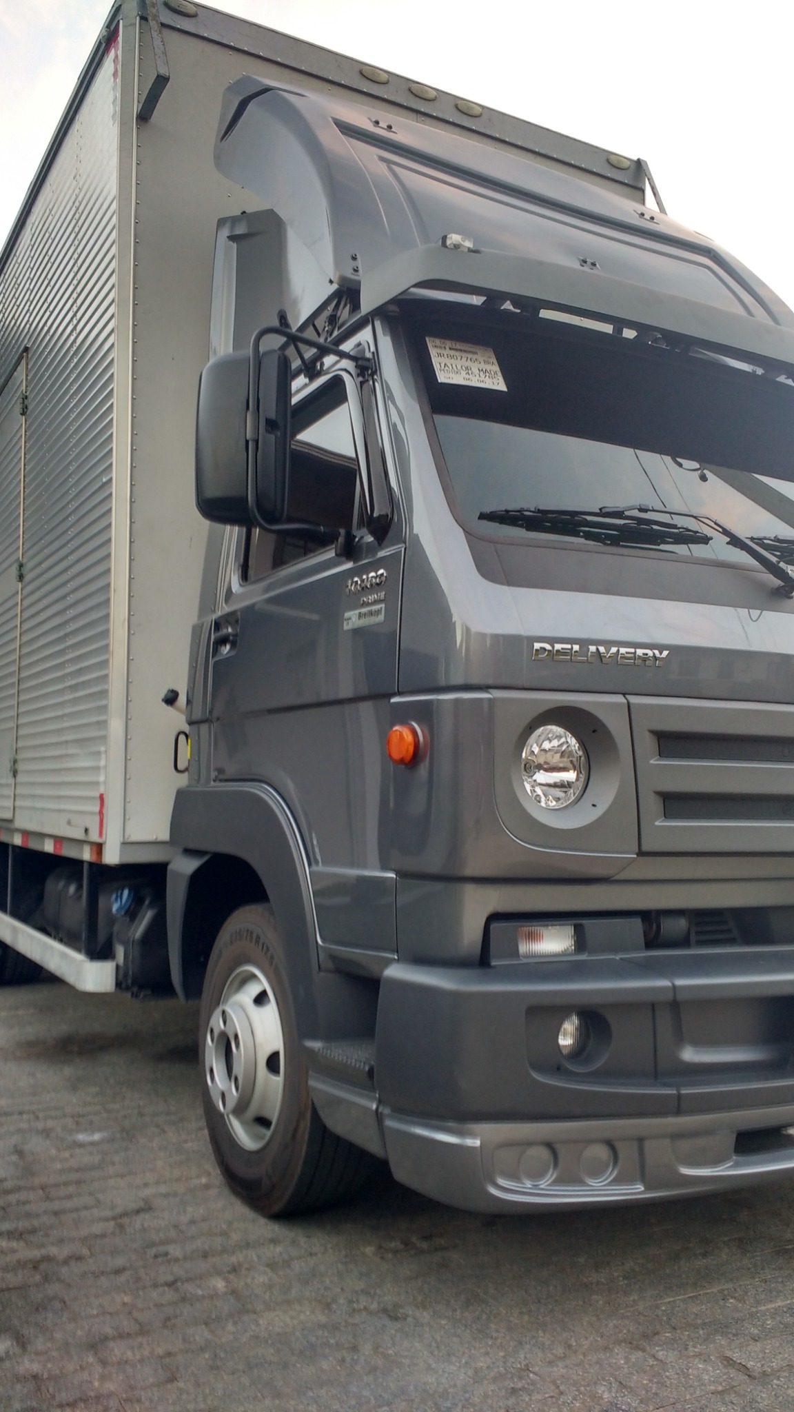 Caminhão baú cinza em composição visual de transporte