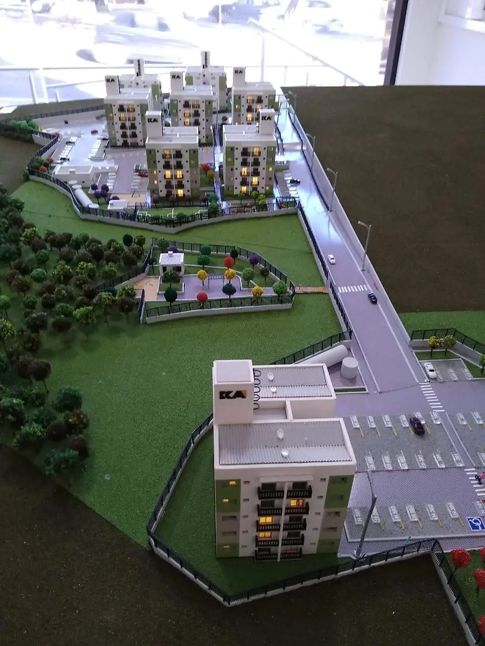 Vista longitudinal de maquete com via, edifícios e paisagismo